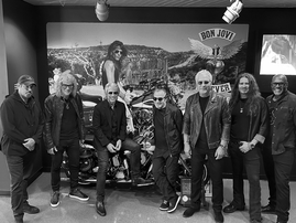 Bon Jovi members pose next to a wall display featuring a motorcycle.png