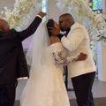 The father of the bride fixes her veil during her first kiss with husband